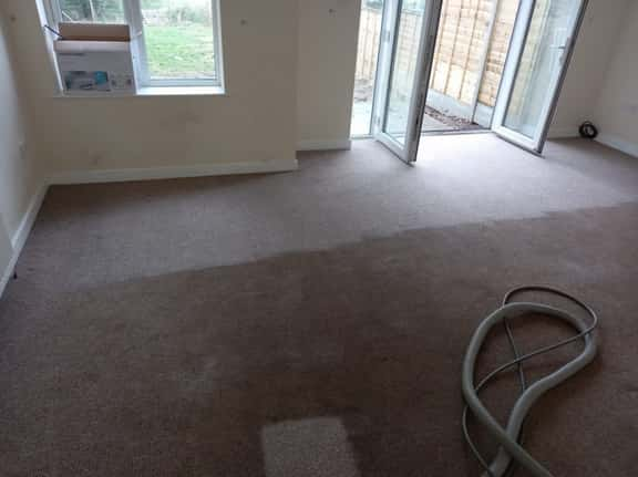 This is a photo of an empty living room with a brown carpet that is in the process of having its carpets steam cleaned works carried out by Borehamwood Carpet Cleaning