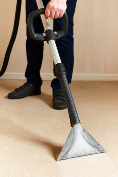 This is a photo of a man steam cleaning a cream carpet, using a professional steam cleaning machine works carried out by Borehamwood Carpet Cleaning