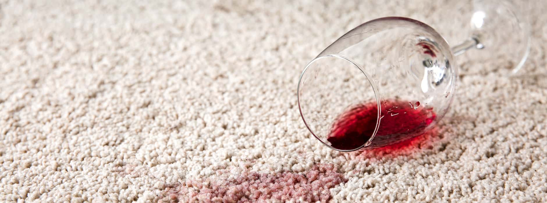 This is a photo of Borehamwood Carpet Cleaning red wine which has been spilt on a cream carpet. The glass is on its side